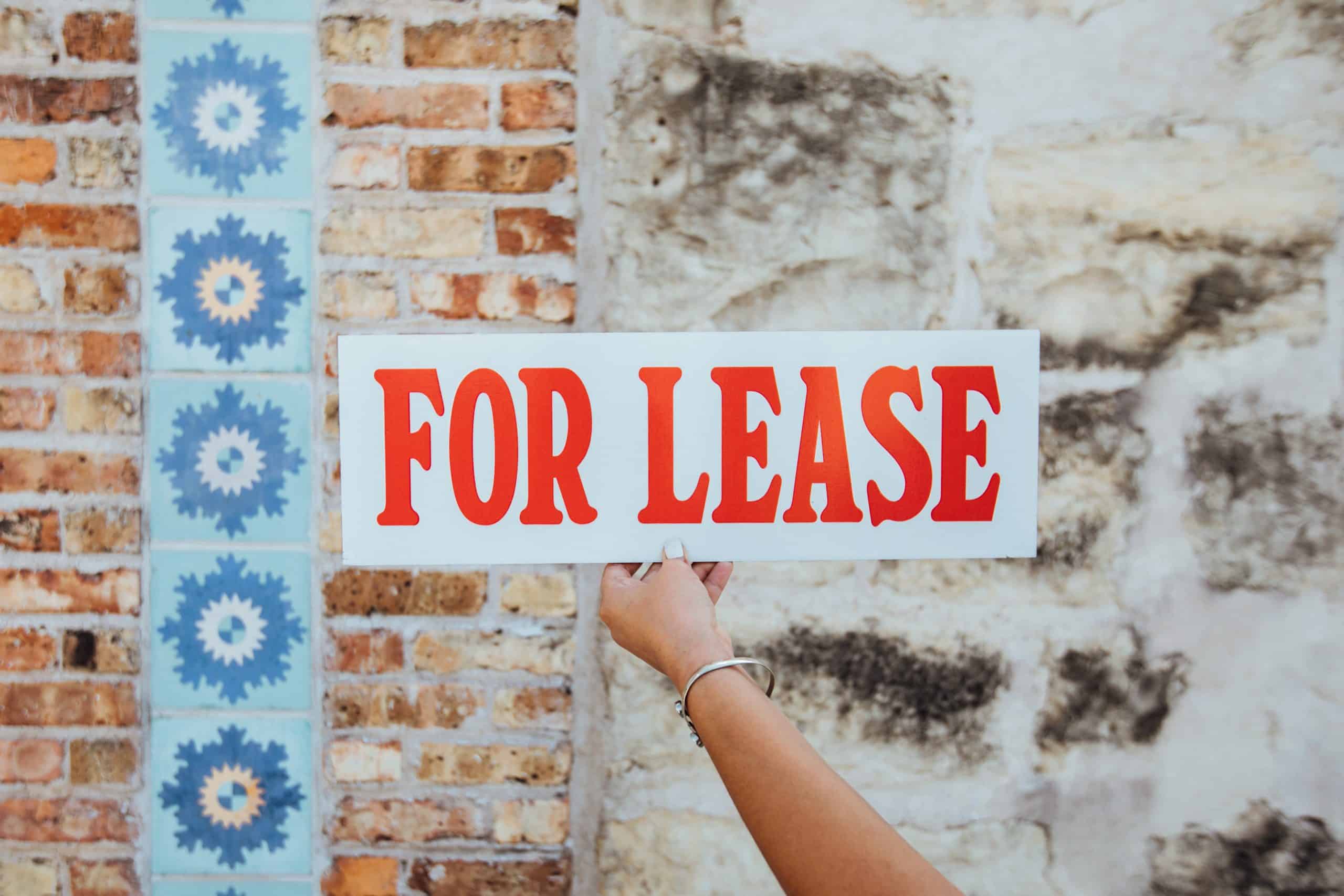a hand holding a for lease sign
