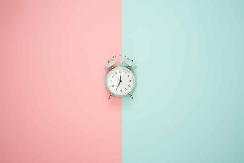 A clock on a pink and blue background.