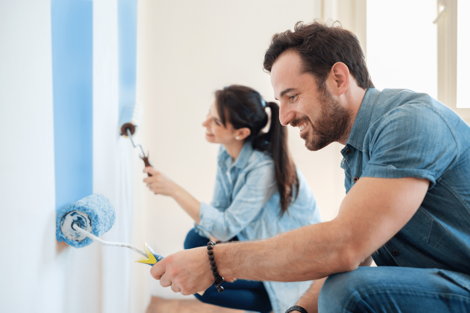 man and woman painting a wall with blue paint