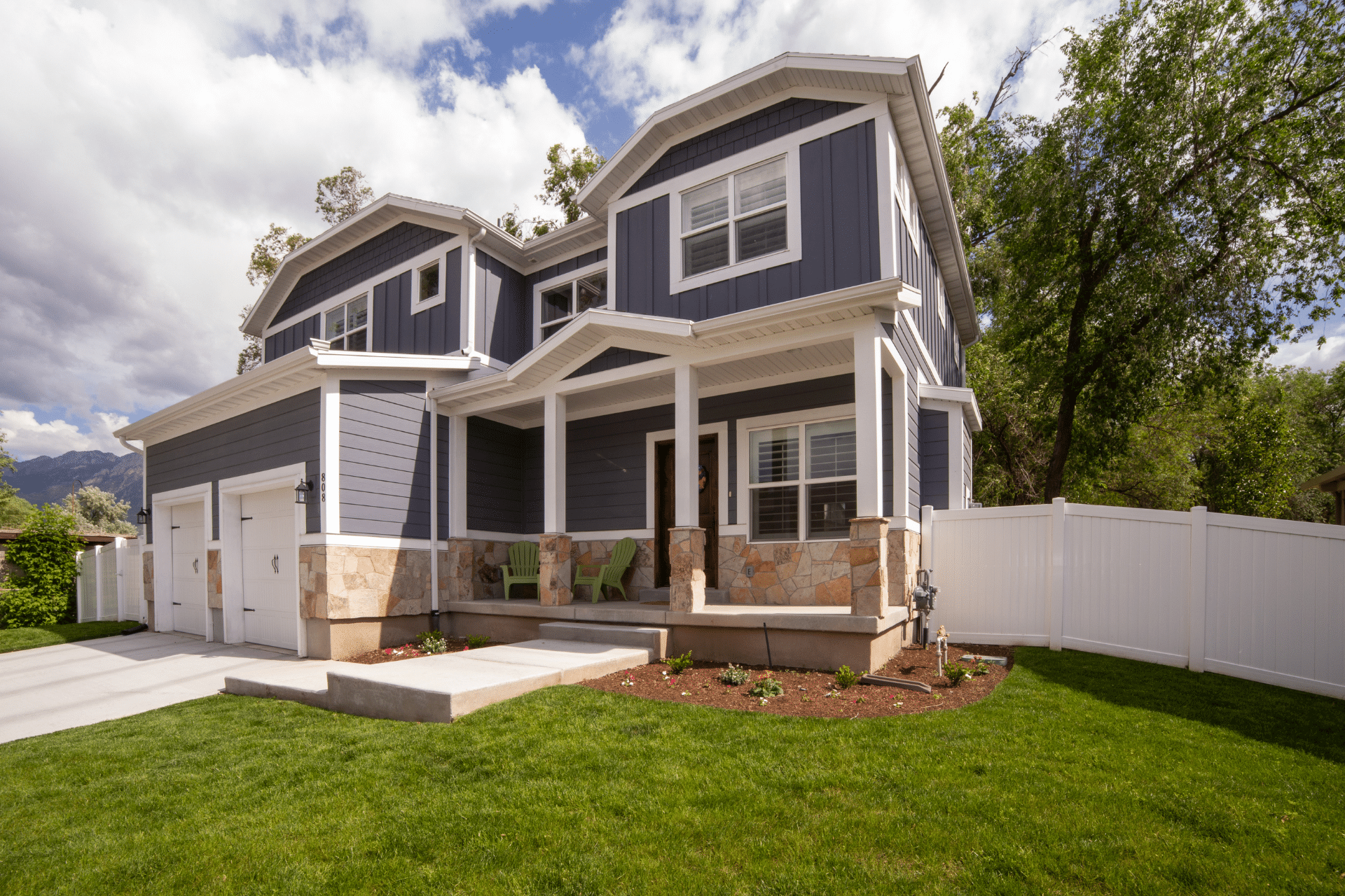 big two story blue house with a green lawn