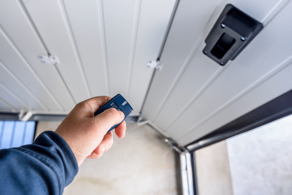 A man's arm holding a garage door clicker pointed at an open garage door