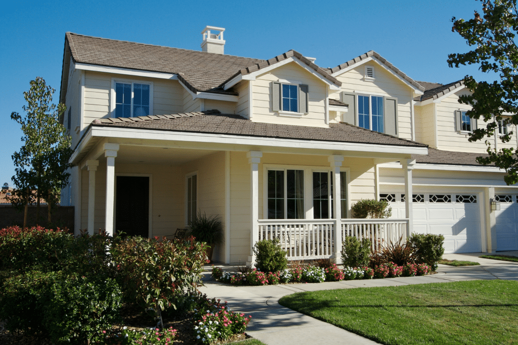 large white 2 story house with a green lawn in the summer