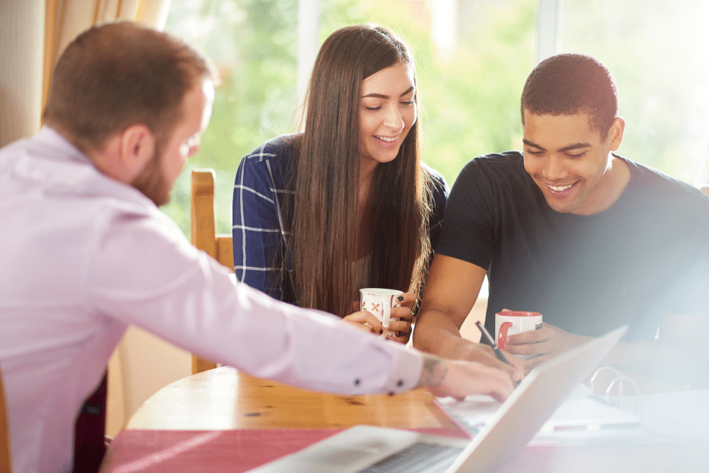 One man showing a woman and man who are smiling some paperwork.