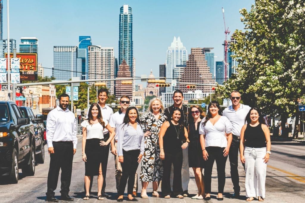 The 1836 Property Management team stands on the road in front of Austin City, smiling and grateful as they reflect on the company highlights of 2023.