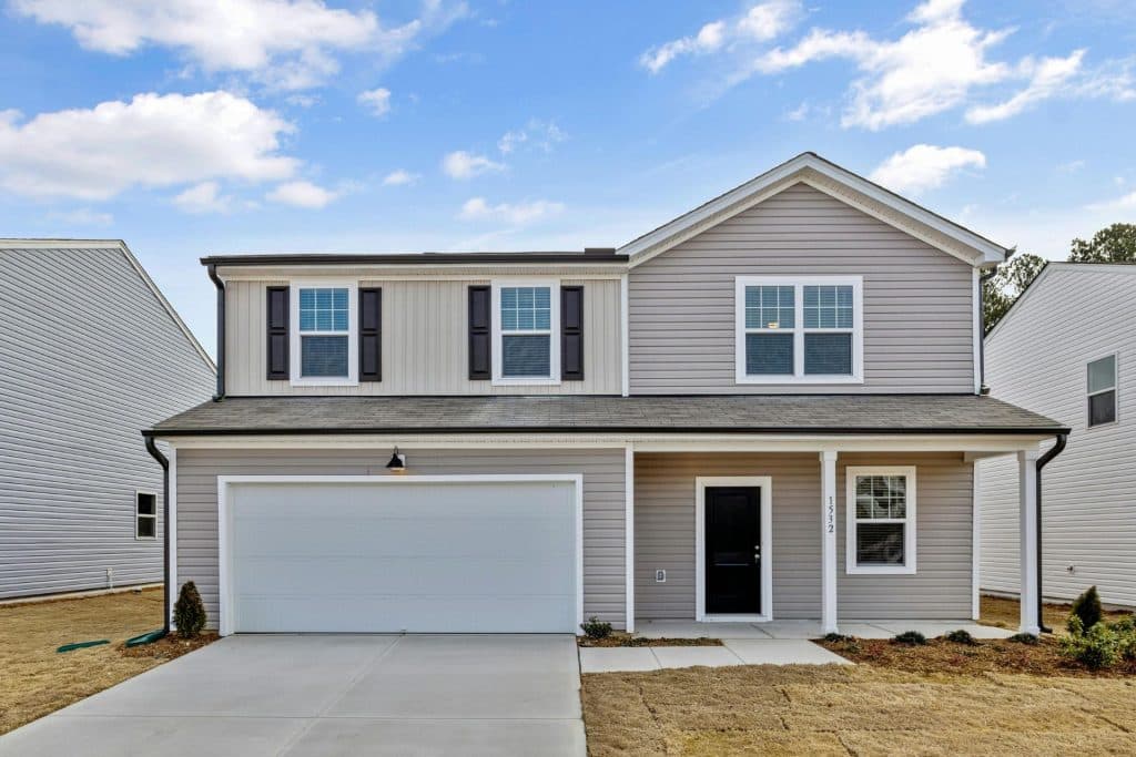 Gray two-story home with upper floor featuring three windows, lower level showcasing a garage door, driveway, window, and entryway - a symbol of remote property management.