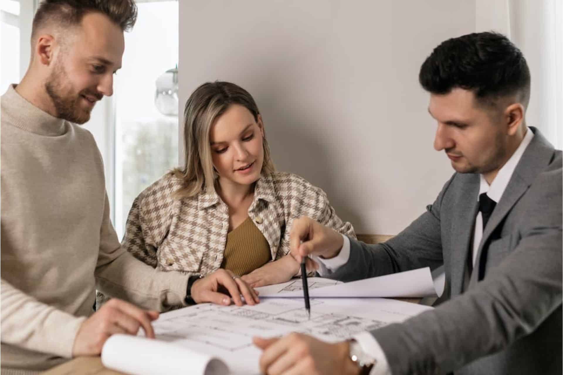 Austin property manager in gray suit presents house plans to enthusiastic couple.